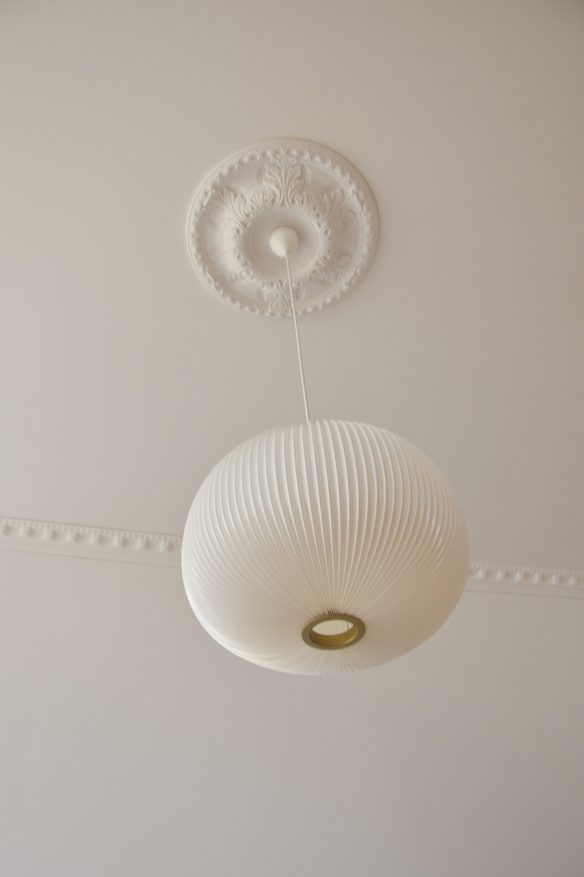 Une rosace encadre un luminaire, associée à des corniches pour une décoration de plafond élégante.